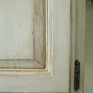 Cette image montre une grande arrière-cuisine parallèle style shabby chic avec un évier 2 bacs, un placard avec porte à panneau encastré, des portes de placard en bois brun, un plan de travail en granite, un électroménager noir, un sol en bois foncé et un îlot central.