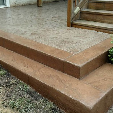 J-Stamped concrete patio with a step under the wood deck
