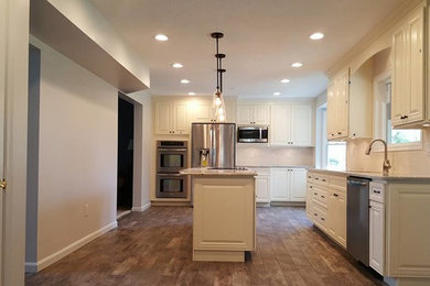 Kitchen - large transitional l-shaped dark wood floor kitchen idea in Baltimore with white cabinets, white backsplash, stainless steel appliances, an island, raised-panel cabinets, granite countertops and an undermount sink