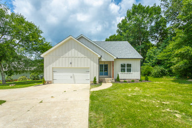 Mid-sized craftsman beige concrete and board and batten exterior home idea in Nashville with a shingle roof and a black roof