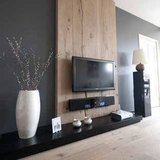 Inredning av ett modernt stort allrum med öppen planlösning, med ett finrum, svarta väggar, ljust trägolv och en väggmonterad TV