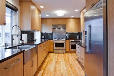Example of a trendy l-shaped enclosed kitchen design in Seattle with a farmhouse sink and flat-panel cabinets
