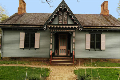 Inspiration for a mid-sized timeless green one-story wood house exterior remodel in Cincinnati with a clipped gable roof and a shingle roof