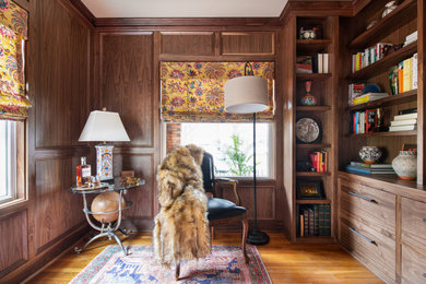 Design ideas for a mid-sized transitional home office in Kansas City with a library, brown walls, medium hardwood floors, a built-in desk, brown floor and panelled walls.