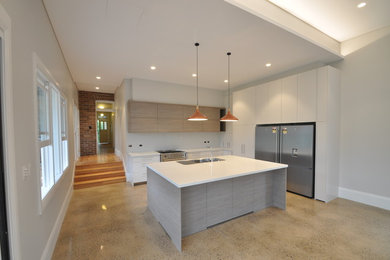 Photo of a large contemporary open plan kitchen in Sydney with a double-bowl sink, flat-panel cabinets, white cabinets, stainless steel appliances, concrete floors and with island.