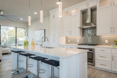 Inspiration for a transitional open plan kitchen in Dallas with an undermount sink, shaker cabinets, white cabinets, metallic splashback, metal splashback, stainless steel appliances, with island, grey floor and white benchtop.