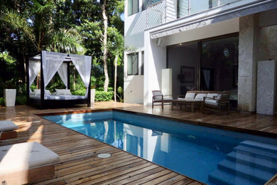 Imagen de piscina alargada exótica de tamaño medio rectangular en patio con paisajismo de piscina y entablado