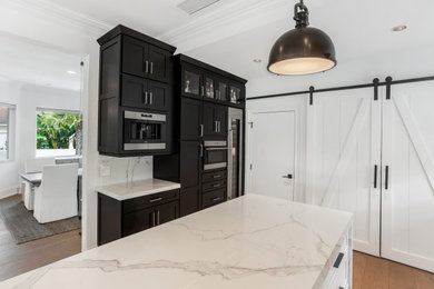 Inspiration for a small transitional single-wall medium tone wood floor and beige floor kitchen remodel in Jacksonville with shaker cabinets, black cabinets, quartz countertops, quartz backsplash, stainless steel appliances and white countertops