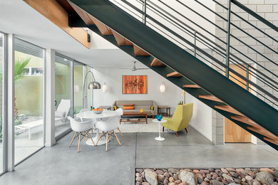 This is an example of a midcentury open concept living room with white walls, concrete floors and grey floor.