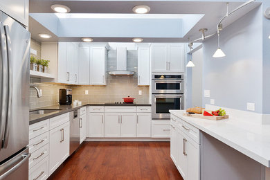 Inspiration for a large contemporary l-shaped eat-in kitchen in San Francisco with a single-bowl sink, shaker cabinets, white cabinets, solid surface benchtops, grey splashback, glass tile splashback, stainless steel appliances, medium hardwood floors and with island.