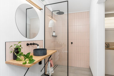 Photo of a mid-sized contemporary 3/4 bathroom in Sydney with a curbless shower, pink tile, a vessel sink, wood benchtops, grey floor, an open shower, beige benchtops, a single vanity and a floating vanity.
