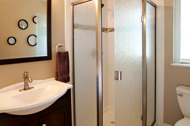 Inspiration for a mid-sized timeless master corner shower remodel in Other with shaker cabinets, dark wood cabinets, a one-piece toilet, beige walls, a pedestal sink and a hinged shower door