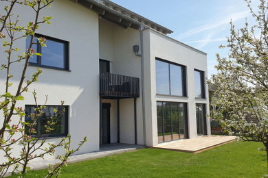 Großes, Dreistöckiges Modernes Haus mit Putzfassade, weißer Fassadenfarbe, Satteldach, Ziegeldach und schwarzem Dach