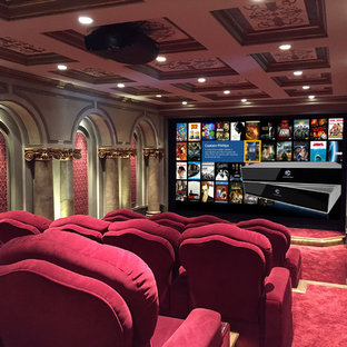 This is an example of an expansive modern enclosed home cinema in Atlanta with red walls, carpet, a projector screen and red floors.
