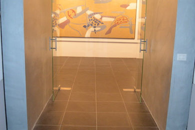 Esempio di una porta d'ingresso moderna di medie dimensioni con pareti con effetto metallico, pavimento in gres porcellanato, una porta a due ante, una porta in vetro e pavimento nero