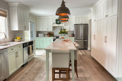 Photo of a transitional open plan kitchen in New York with an undermount sink, recessed-panel cabinets, quartzite benchtops, beige splashback, ceramic splashback, stainless steel appliances, with island and beige benchtop.