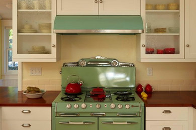 Eat-in kitchen - mid-sized transitional u-shaped medium tone wood floor eat-in kitchen idea in Denver with a farmhouse sink, shaker cabinets, white cabinets, wood countertops, beige backsplash, ceramic backsplash, colored appliances and an island