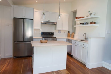 Transitional medium tone wood floor eat-in kitchen photo in Philadelphia with an undermount sink, shaker cabinets, white cabinets, quartz countertops, white backsplash, ceramic backsplash, stainless steel appliances and an island