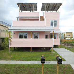 Exempel på ett modernt rosa trähus, med två våningar