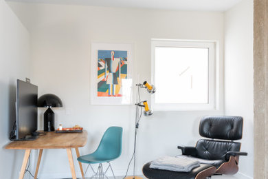 Imagen de despacho moderno sin chimenea con paredes blancas, suelo de cemento, escritorio independiente y suelo gris