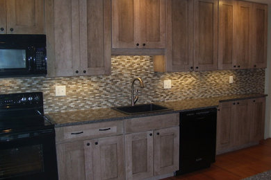 Kitchen - contemporary light wood floor kitchen idea in DC Metro with a drop-in sink, distressed cabinets, quartz countertops, brown backsplash, mosaic tile backsplash, black appliances and shaker cabinets