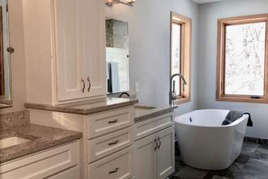 Photo of a mid-sized contemporary master bathroom in Minneapolis with recessed-panel cabinets, white cabinets, a freestanding tub, grey walls, ceramic floors, an undermount sink, engineered quartz benchtops, multi-coloured floor and multi-coloured benchtops.