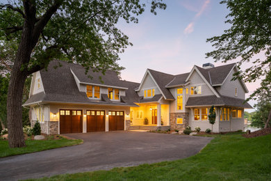 This is an example of a large beach style two-storey grey house exterior in Minneapolis with concrete fiberboard siding, a gable roof, a mixed roof, a black roof and shingle siding.