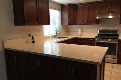 Example of a mid-sized classic u-shaped ceramic tile and beige floor eat-in kitchen design with a double-bowl sink, shaker cabinets, dark wood cabinets, limestone countertops, stainless steel appliances and a peninsula