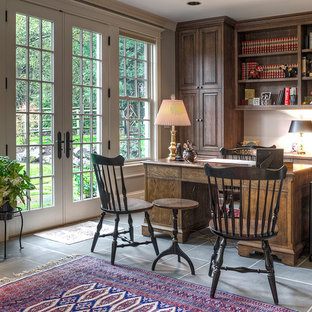 Inredning av ett lantligt stort arbetsrum, med grå väggar, ett fristående skrivbord, skiffergolv och grått golv