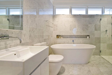 Inspiration for a large contemporary master white tile and stone tile marble floor and gray floor bathroom remodel in San Diego with flat-panel cabinets, white cabinets, white walls, a trough sink, a one-piece toilet and a hinged shower door