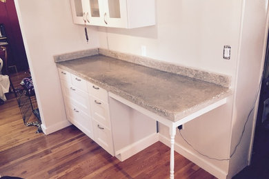 Kitchen photo in New York with white cabinets, concrete countertops and an island