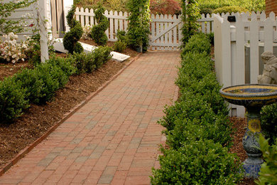 Photo of a mid-sized traditional partial sun side yard brick garden path in Other for spring.