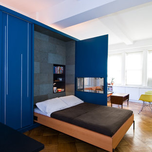 Diseño de dormitorio actual con paredes azules y suelo de madera en tonos medios