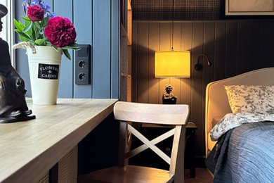 На фото: хозяйская, серо-белая спальня среднего размера в скандинавском стиле с черными стенами, полом из ламината, желтым полом, стенами из вагонки и рабочим местом без камина с