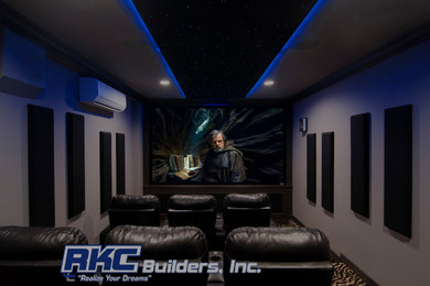 Ejemplo de cine en casa cerrado de tamaño medio con paredes grises, moqueta, pantalla de proyección y suelo multicolor