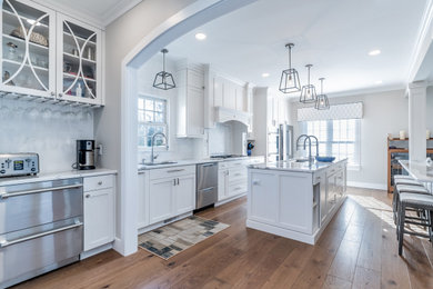 Large transitional galley light wood floor eat-in kitchen photo in Other with an undermount sink, recessed-panel cabinets, white cabinets, quartz countertops, white backsplash, marble backsplash, stainless steel appliances, two islands and white countertops