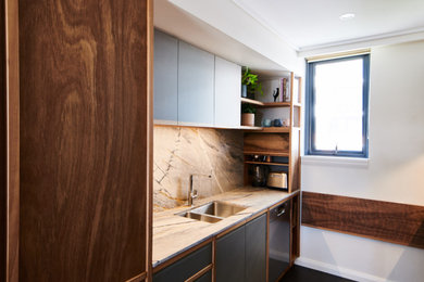 This is an example of a small contemporary galley separate kitchen in Sydney with an undermount sink, beaded inset cabinets, medium wood cabinets, quartzite benchtops, multi-coloured splashback, stone slab splashback, stainless steel appliances, no island, grey floor and multi-coloured benchtop.