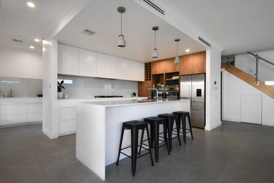 Cette photo montre une grande cuisine ouverte moderne en L avec un évier encastré, des portes de placard blanches, une crédence grise et îlot.