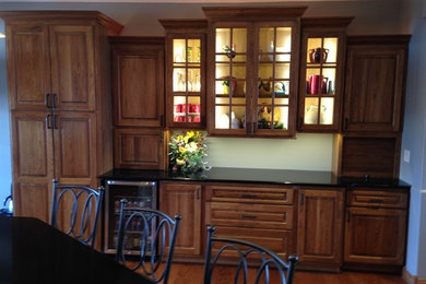 Eat-in kitchen - mid-sized traditional u-shaped medium tone wood floor and brown floor eat-in kitchen idea in Other with raised-panel cabinets, medium tone wood cabinets, granite countertops, stainless steel appliances, an undermount sink, beige backsplash, porcelain backsplash and an island