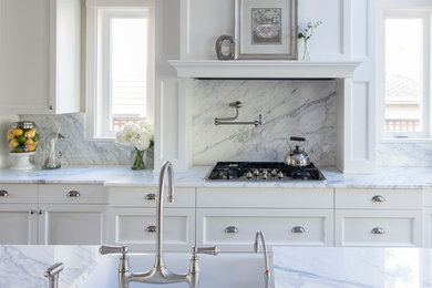 Eat-in kitchen - traditional dark wood floor and brown floor eat-in kitchen idea in Denver with a farmhouse sink, white cabinets, marble countertops, white backsplash, marble backsplash, stainless steel appliances, an island and white countertops