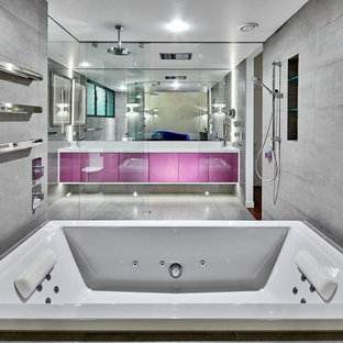 Foto de cuarto de baño principal, moderno, extra grande, con armarios con paneles lisos, puertas de armario violetas, bañera encastrada, ducha a ras de suelo, baldosas y/o azulejos grises, baldosas y/o azulejos de piedra, paredes blancas, suelo de baldosas de cerámica, lavabo integrado, encimera de cuarzo compacto, suelo gris y ducha abierta