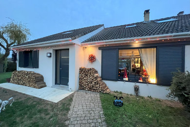 Aménagement d'une façade de maison contemporaine en béton de taille moyenne et à un étage avec un toit en tuile et un toit marron.