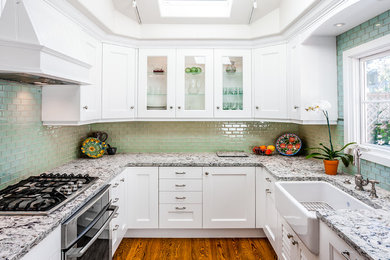 Mid-sized country u-shaped separate kitchen in San Francisco with a farmhouse sink, shaker cabinets, white cabinets, granite benchtops, green splashback, subway tile splashback, stainless steel appliances, medium hardwood floors and no island.