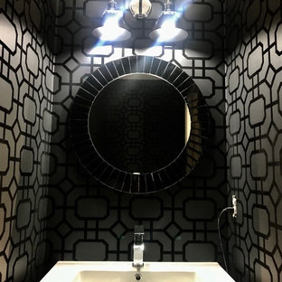 Mittelgroße Moderne Gästetoilette mit verzierten Schränken, schwarzen Schränken, Wandtoilette mit Spülkasten, schwarzer Wandfarbe, braunem Holzboden, integriertem Waschbecken, Glaswaschbecken/Glaswaschtisch, braunem Boden und weißer Waschtischplatte in Boston