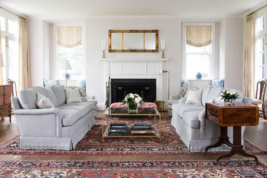 Elegant medium tone wood floor and brown floor living room photo in Baltimore with white walls and a standard fireplace
