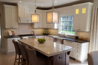 This is an example of a mid-sized transitional l-shaped eat-in kitchen in New York with a farmhouse sink, shaker cabinets, white cabinets, multi-coloured splashback, matchstick tile splashback, stainless steel appliances and brown floor.