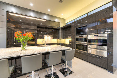 This is an example of a mid-sized modern u-shaped separate kitchen in Austin with an undermount sink, flat-panel cabinets, grey cabinets, granite benchtops, beige splashback, glass sheet splashback, stainless steel appliances, porcelain floors, with island and beige floor.
