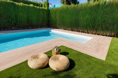 Imagen de piscina alargada minimalista de tamaño medio en forma de L en patio trasero con paisajismo de piscina y suelo de baldosas
