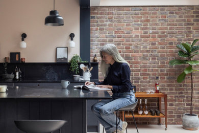 Design ideas for a medium sized contemporary single-wall kitchen/diner in Hertfordshire with a built-in sink, flat-panel cabinets, blue cabinets, engineered stone countertops, black splashback, engineered quartz splashback, black appliances, light hardwood flooring, an island and black worktops.