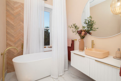 This is an example of a small contemporary master bathroom in Newcastle - Maitland with white cabinets, a freestanding tub, a shower/bathtub combo, a one-piece toilet, orange tile, ceramic tile, orange walls, marble floors, a vessel sink, engineered quartz benchtops, white floor, a shower curtain, white benchtops, a single vanity and a floating vanity.